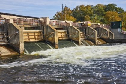 Hydroelectric dam with multiple spillway gates releasing water into a river.